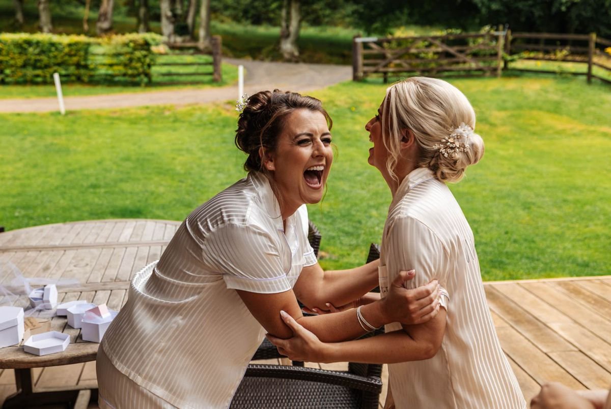 bride best friend laughing at hidden river barn