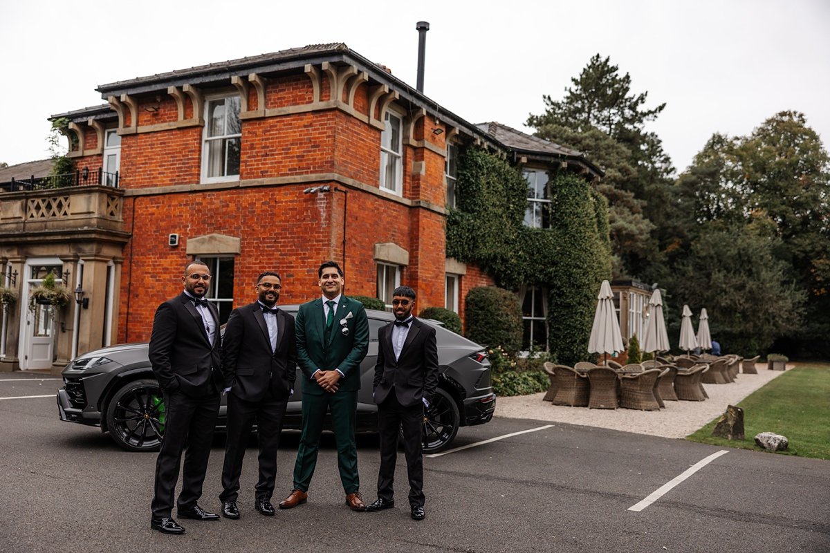grooms men infront of Bartle Hall wedding venue luxury car behind 